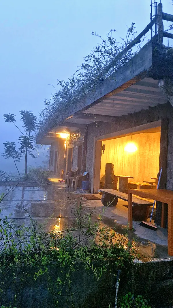 Villa batu dengan lampu hangat saat kabut